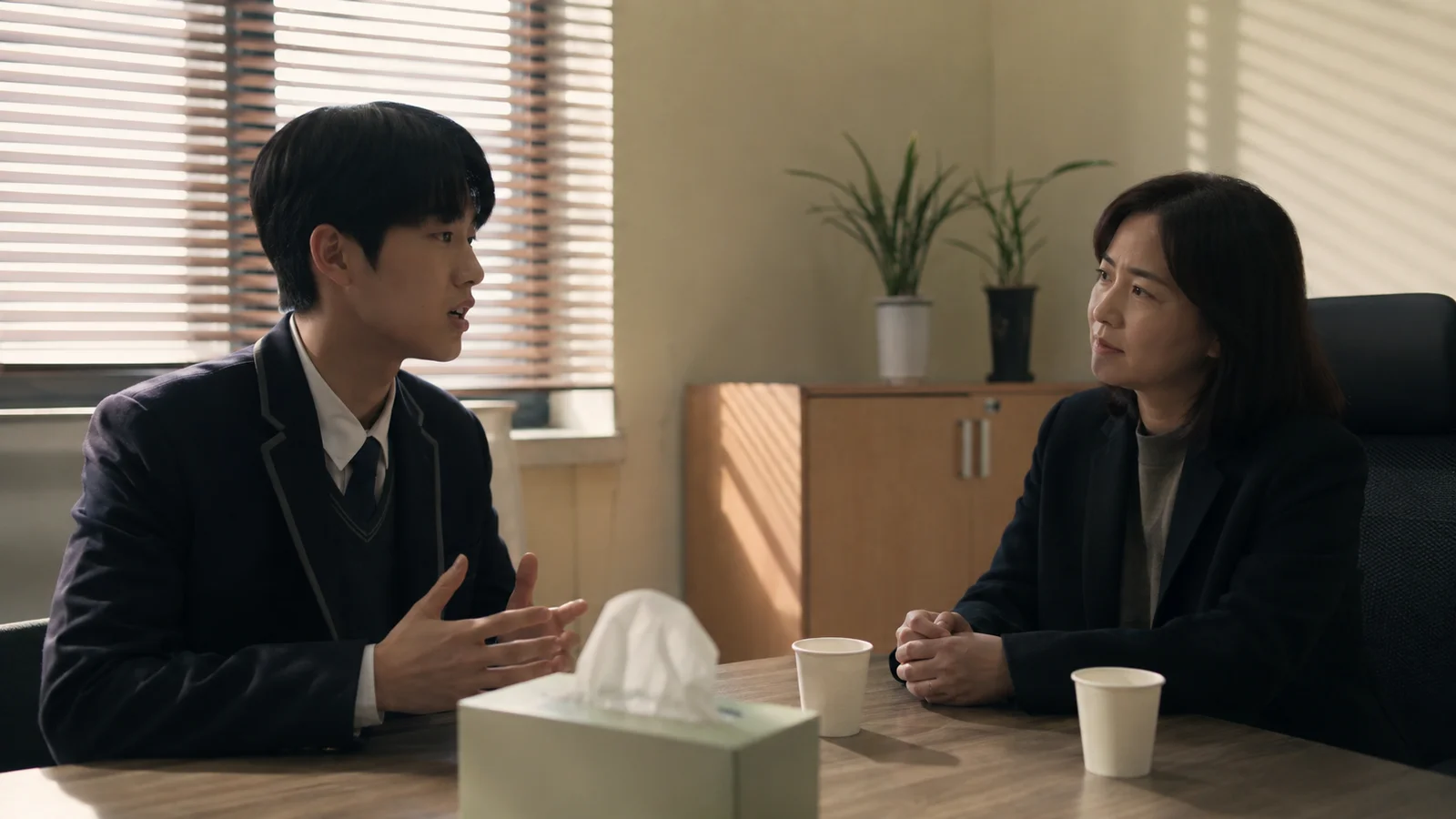 방과 후 상담실에서 상담교사와 마주 앉아 이야기하는 한국 남학생