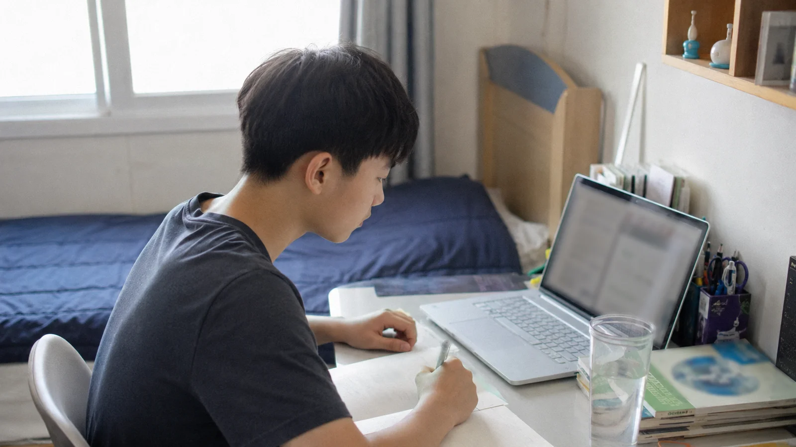 낮에 집 책상에서 노트북 화면으로 원격수업을 듣는 한국 중학생