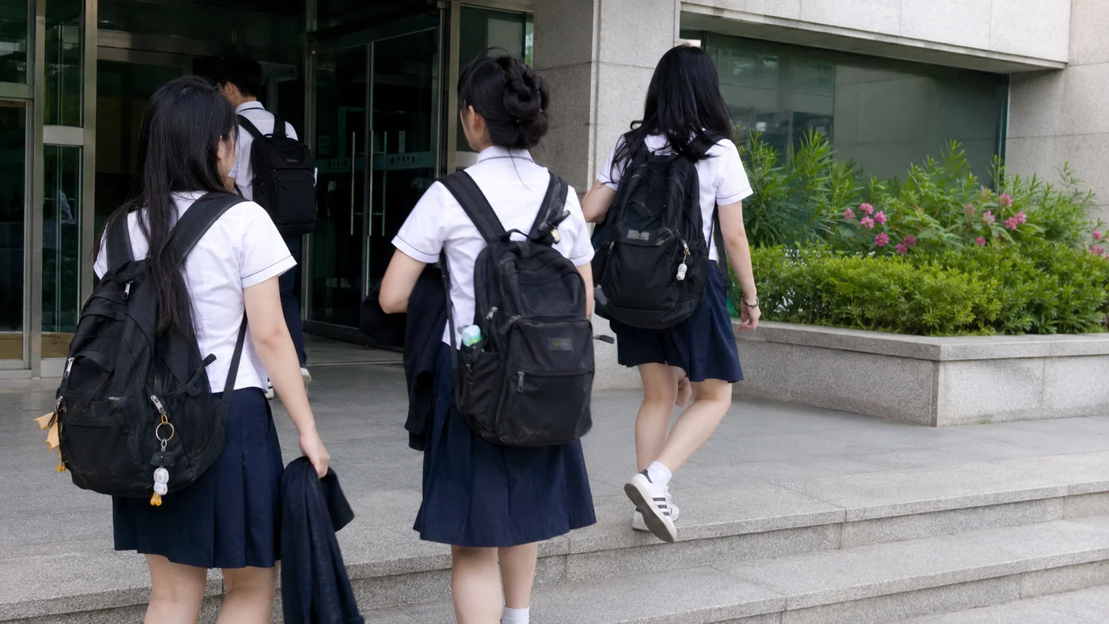 한국 학교 본관 현관 계단을 오르는 교복 입은 학생들의 뒷모습