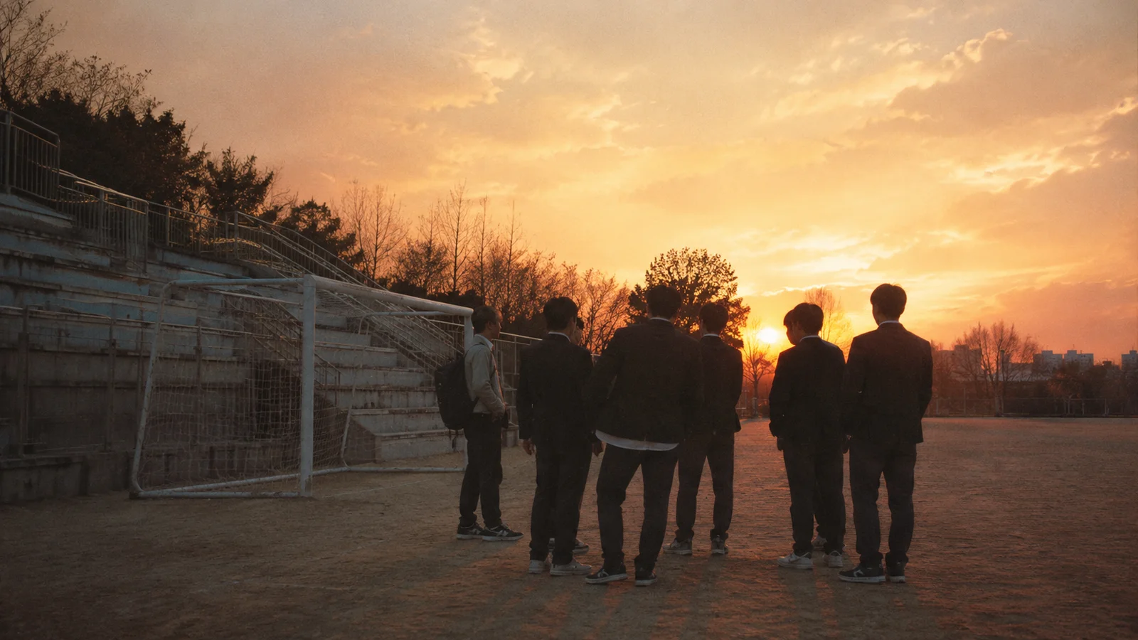 저녁 무렵 학교 운동장 구석에 모여 있는 학생들의 실루엣
