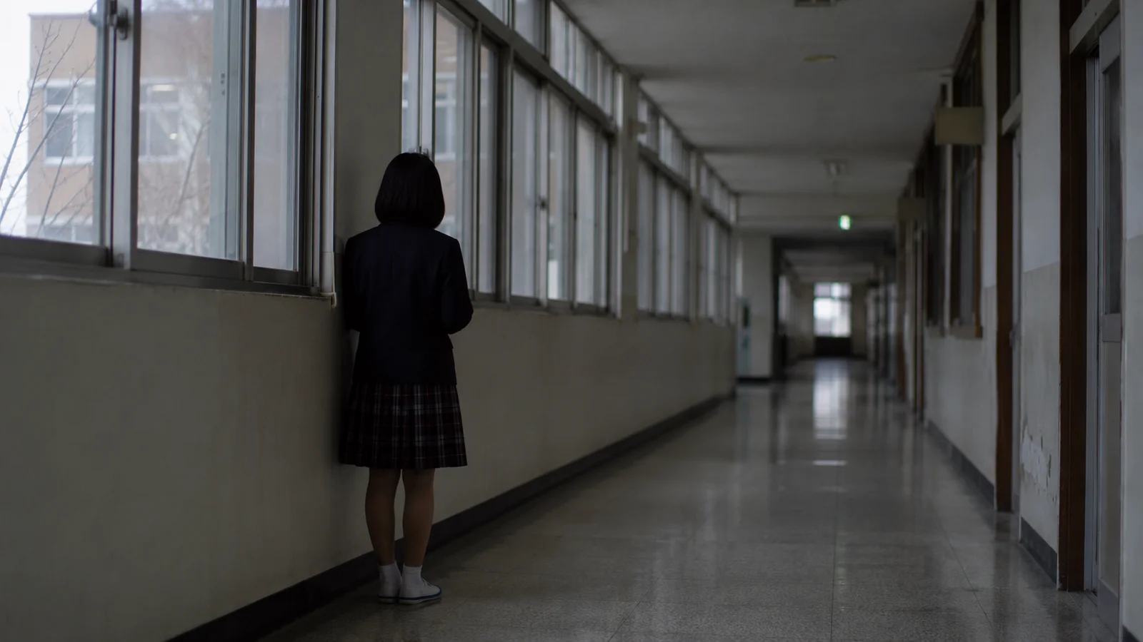 어둑한 학교 복도에 홀로 서 있는 학생